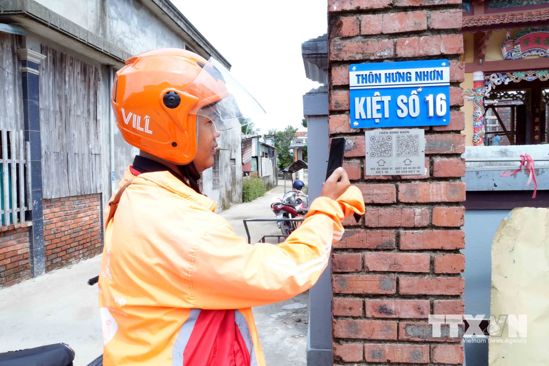 Shipper tìm địa chỉ giao hàng đến tận nhà người dân thông qua mã QR gắn ở đầu ngõ. (Ảnh: Tá Chuyên/TTXVN)